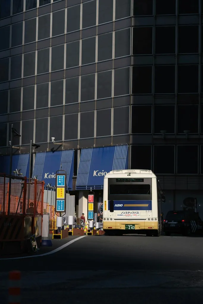 A city bus on a sunlit street beside a glass office building
