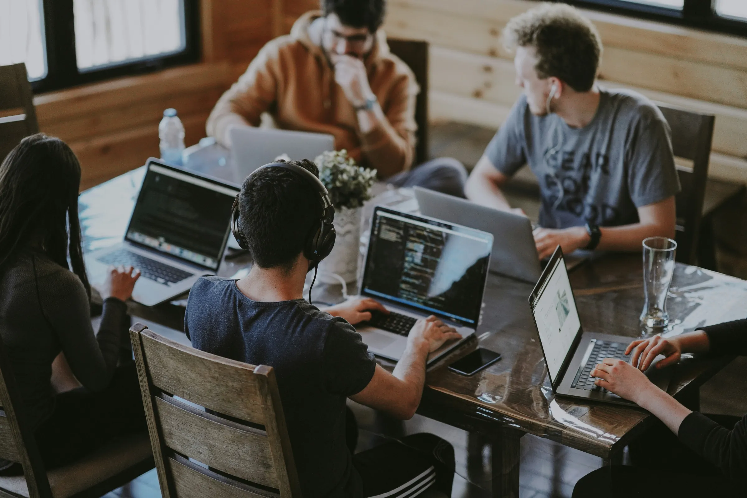 A team collaborating around laptops at a wooden office table
